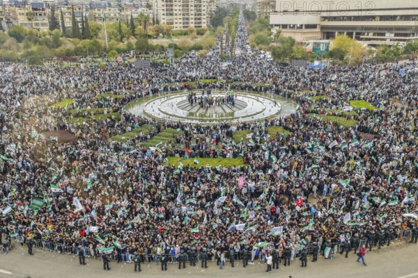 Damascus, Syria – December 08, 2025: A drone view shows thousands of people gathering in the iconic Umayyad Square in central Damascus, raising Syrian flags to celebrate the first anniversary of the fall of the Assad regime and the end of a devastating 14-year war that claimed hundreds of thousands of lives, Damascus, Damascus, Syria