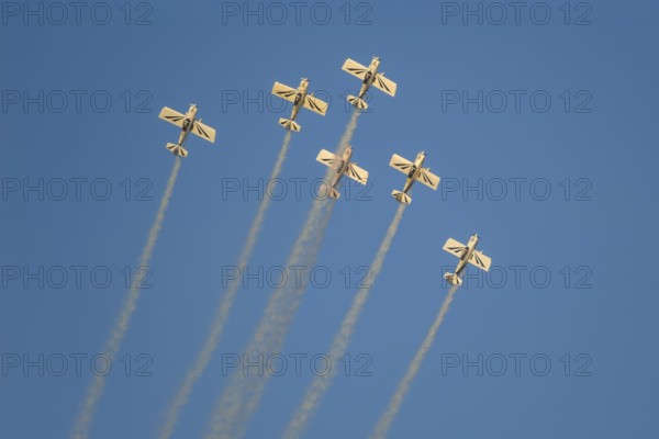 Stunt aerobatic planes performing stunts in blue sky with smoke trail. Concept of teamwork, collaboration, coordination, trust, precision, difficulty, challenge, speed, synergy