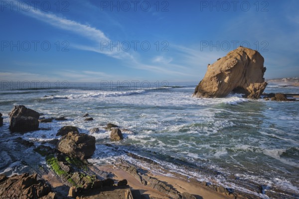 Penedo do Guincho, a large boulder rock arch at Praia da Santa Cruz, Portugal, with ocean waves and sandy beach