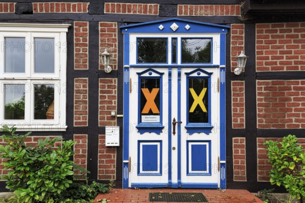 Characteristic half-timbered house, façade detail, blue white door, yellow X symbol, resistance against nuclear power, anti-nuclear power movement, peaceful protest against nuclear energy, nuclear waste transportation, Lüchow-Dannenberg, Wendland, Germany