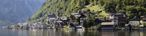 Idyllic seascape with picturesque houses on the shore in front of wooded mountains, Austria, Hallstatt, panorama