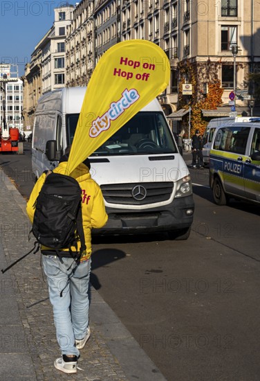 Cityscape, A man carrying the advertising banner of the Hop on Hop off buses from City Circle, Berlin, Germany