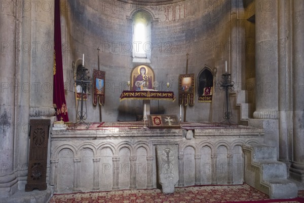Historic church altar with icons and candles in a stone room, illuminated by windows, Goshavank Monastery, Tavush Province, Armenia
