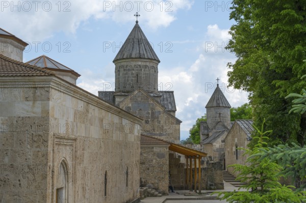 Monastery with stone buildings and towers under partly cloudy sky, surrounded by trees, Haghartsin monastery, Hagarzin, Tavush province, Armenia