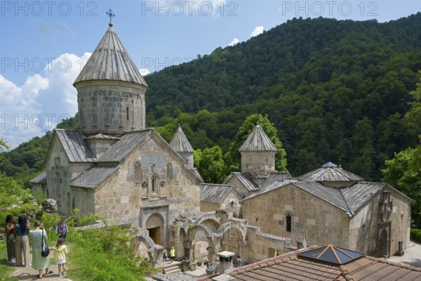 Monastery complex with towers and stone buildings against green mountains and sky background, Haghartsin Monastery, Hagarzin, Tavush Province, Armenia