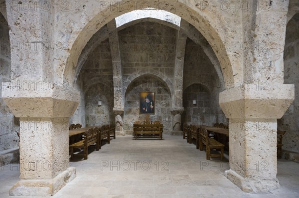 Stone vault with wooden furniture and paintings on the wall, sparse interior, refectory interior, dining room, Haghartsin monastery, Hagarzin, Tavush province, Armenia