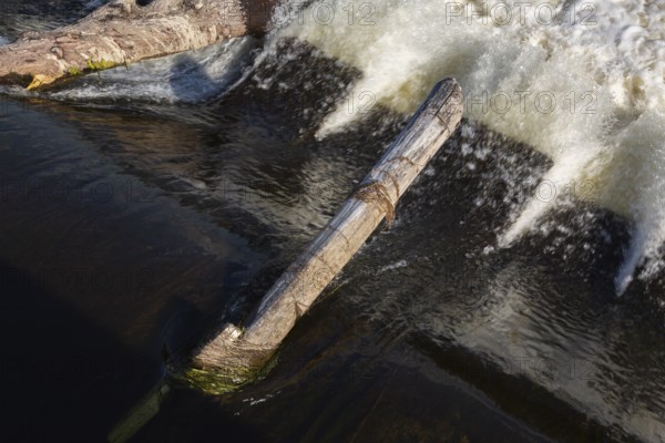 Driftwood logs jammed on hydraulic jumps at base of water diversion dam on Des Mille-Iles RIver in summer, Terrebonne, Quebec, Canada