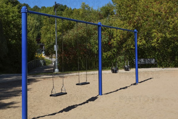 Swings installed in sandy ground in kids playground in city park in late summer, Parc du Grand-Coteau, Mascouche, Quebec, Canada