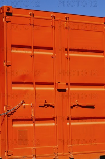 Locked bright fluorescent orange painted metal box shaped shipping container with doors locked shut, Quebec, Canada