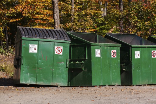 Green painted metal with black plastic lid industrial size waste bins for depositing garbage and non recyclable materials in, Quebec, Canada