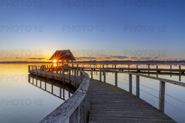 Wooden jetty on Lake Hemmelsdorf / Hemmelsdorfer See at sunrise in spring near Lübeck, Schleswig-Holstein, Germany