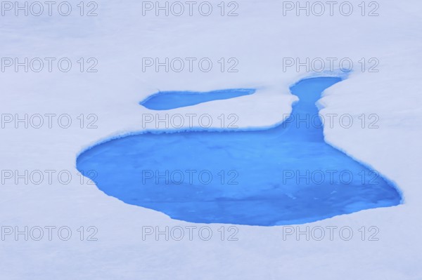 Aerial view over vivid blue water of meltpond / melt pond / meltwater pool on sea ice in the Arctic Ocean at Svalbard / Spitsbergen, Norway