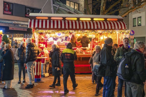 A festively illuminated Christmas market stand with lots of people in a wintry evening mood, Christmas market 2025, Nagold, Black Forest, Calw district, Germany