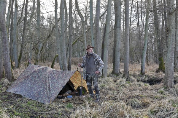 Camp of a nature photographer, nature photographer in front of his camouflage camp in the Erlenbruch Forest, Peenetal nature park Park, Mecklenburg-Western Pomerania, Germany
