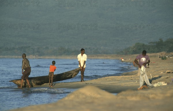 Men letting dugout into water, boy, Lake Malawi, Kande, Malawi, Africa, July 2000, vintage, retro, old, historical