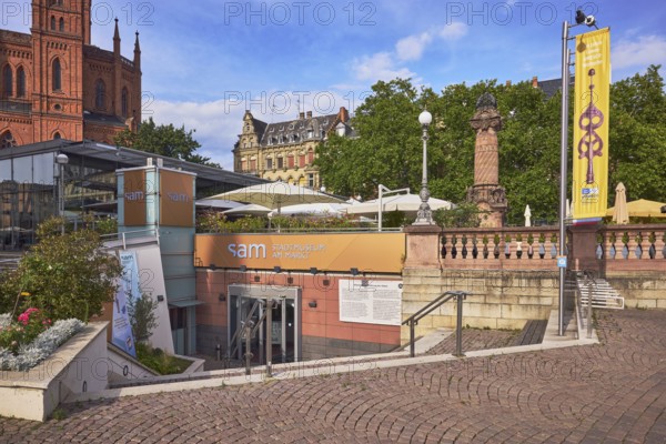 Sam - Stadtmuseum am Markt, entrance, staircase, advertising flag on flagpoles, flower bed, sandstone wall, outdoor area of a restaurant, buildings, historic houses, trees, blue sky, cumulus clouds, market square, Wiesbaden, state capital, district-free city, Hesse, Germany