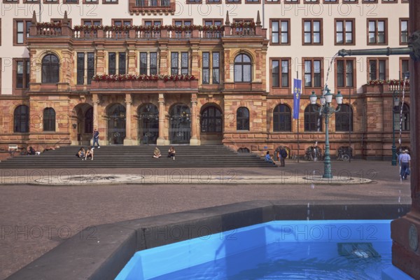 Market fountain, sandstone fountain, town hall, neo-Renaissance style, architect Georg von Hauberrisser, façade with windows, stairs, columns, paving stone square, lantern, flag city of Wiesbaden, pedestrian as accessories, sunny, diffuse light, Schlossplatz square, Wiesbaden, state capital, district-free city, Hesse, Germany