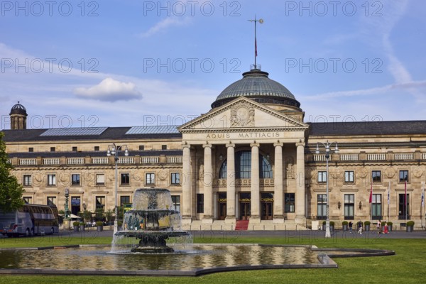 Spa hotel, neo-classical style, architect Friedrich von Thiersch, inscription Aquis Mattiacis, columns, sandstone building material, garden, green area, lawn, cascade fountain, blue sky, cumulus clouds, evening light, Kurhausplatz, Wiesbaden, state capital, district-free city, Hesse, Germany