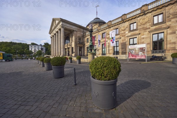 Spa hotel, architectural style neoclassicism, architect Friedrich von Thiersch, building material sandstone, facade with windows, columns, planter with boxwood (Buxus sempervirens), milky blue sky, diffuse light, slightly sunny, evening light, square Kurhausplatz, Wiesbaden, state capital, independent city, Hesse, Germany