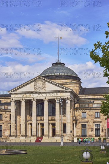 Spa hotel, neo-classical style, architect Friedrich von Thiersch, columns, Aquis Mattiacis inscription, green spaces, tree, lawn, blue sky, cumulus clouds, Kurhausplatz square, Wiesbaden, state capital, district-free city, Hesse, Germany