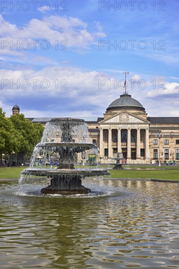 Spa hotel, neo-classical style, architect Friedrich von Thiersch, columns, gardens, trees, lawn, bowling green, abstract reflections on the water surface, blue sky, cumulus clouds, Kurhausplatz square, Wiesbaden, state capital, district-free city, Hesse, Germany