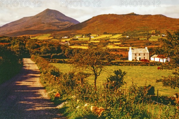 Farmland and rural landscape country road leading towards Derryveagh Mountains mountain range, County Donegal, Ireland 1960s