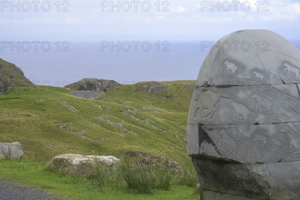 Stone monument with animal representations in the background Eire sign, on the way to the Slieve League cliffs, West Donegal, County Donegal, Ireland