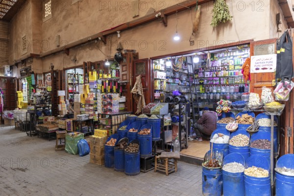 A colorful market stand full of spices, genes and products with a retailer inside a small shop, Marrakech, Medina in Morocco