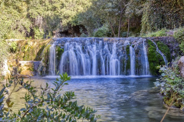 Fascinating waterfall flowing over green moss rocks into a natural basin, El Kelaa wild stream in Morocco