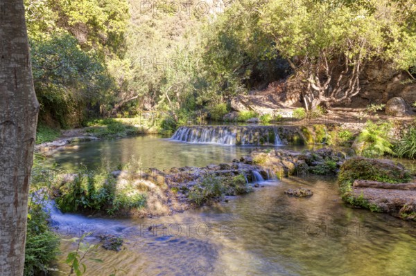 Gentle waterfall on a river surrounded by trees, playing with light and shadow, El Kelaa torrent in Morocco