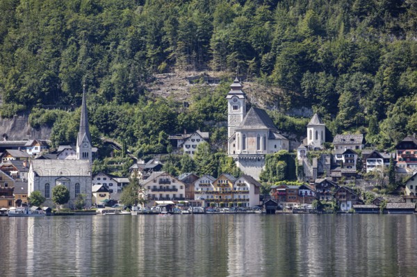 A, Hallstatt, A picturesque village with a lakeside church against a wooded mountain backdrop, Austria