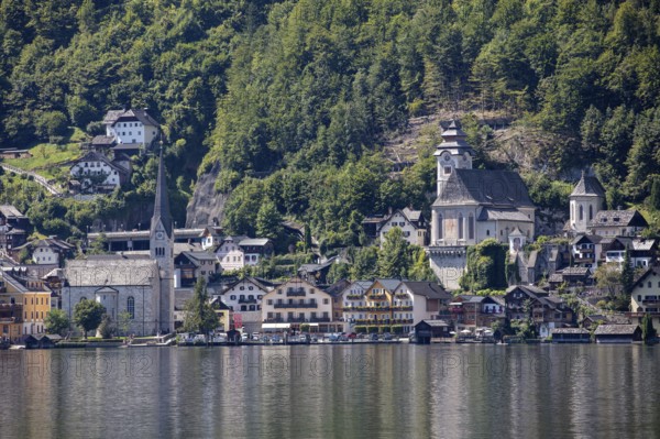 A, Hallstatt, A picturesque lakeside village with church in front of wooded mountains, Austria