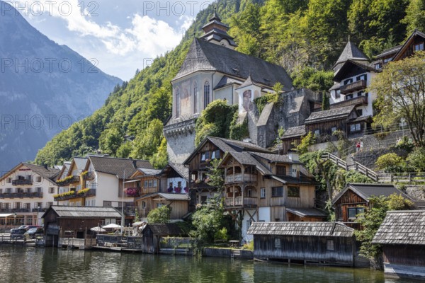 A, Hallstatt, picturesque village with characteristic wooden houses on the lakeside in front of a mountain wall, Austria