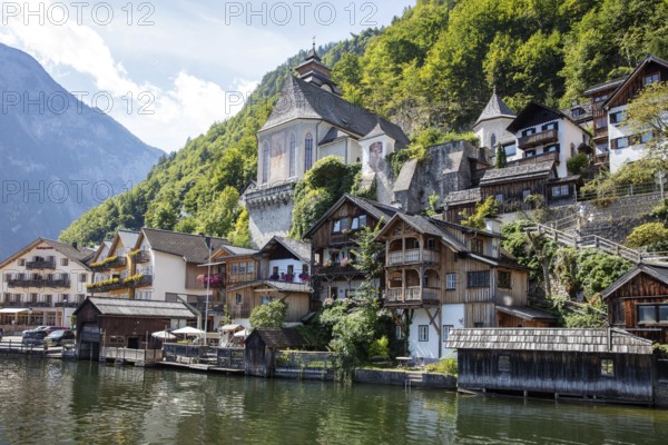A, Hallstatt, houses on the water in front of green mountains, traditional architecture in picturesque surroundings, Austria