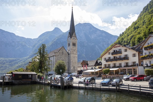 A, Hallstatt, church next to a lake in front of impressive mountains and clouds, quiet scenery, Austria