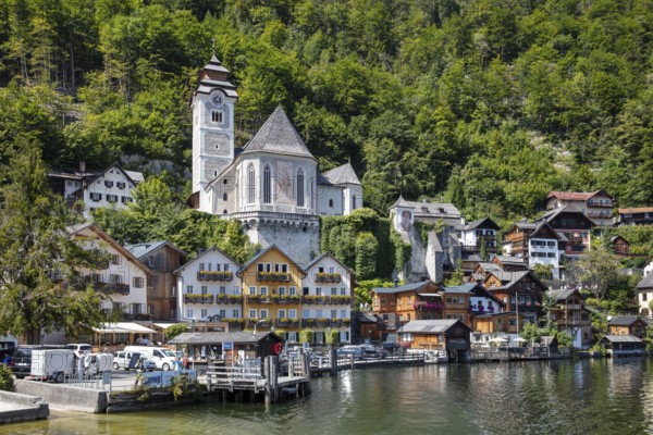 A, Hallstatt, White Church and picturesque houses on the water, surrounded by green mountains, Austria