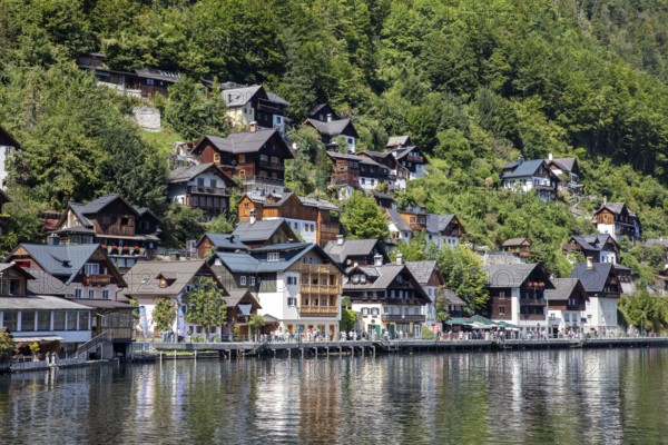A, Hallstatt, lakeside village with numerous wooden houses, surrounded by lush greenery and peaceful atmosphere, Austria