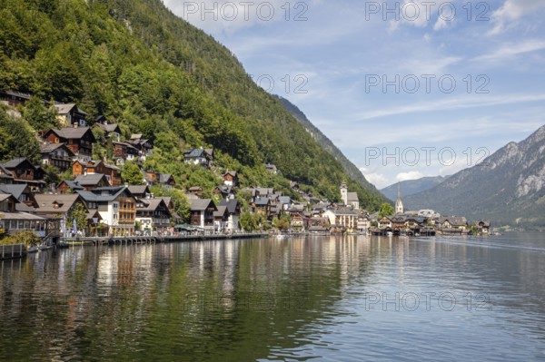 A, Hallstatt, panorama of a picturesque lakeside village with mountains in the background and a church, Austria