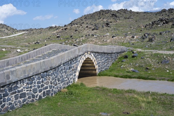 Stone bridge over a small river surrounded by rocky landscape under blue sky, bridge near Cevirme, Dogubayazit, Dogubayazit, Dogubeyazit, Agri Province, Agri, Eastern Anatolia, Anatolia, Turkey