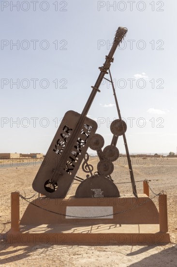 Metal sculpture of a giant guitar in the desert as an outdoor work of art