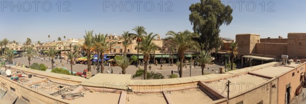 A traditional Moroccan square with palm trees and people in sunny weather