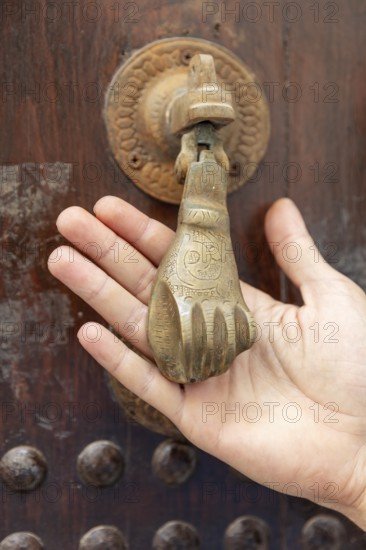 Antique brass door knocker in the shape of a hand, worked with great detail
