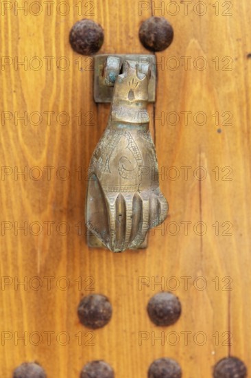 Hand-shaped metal knocker on a wooden door