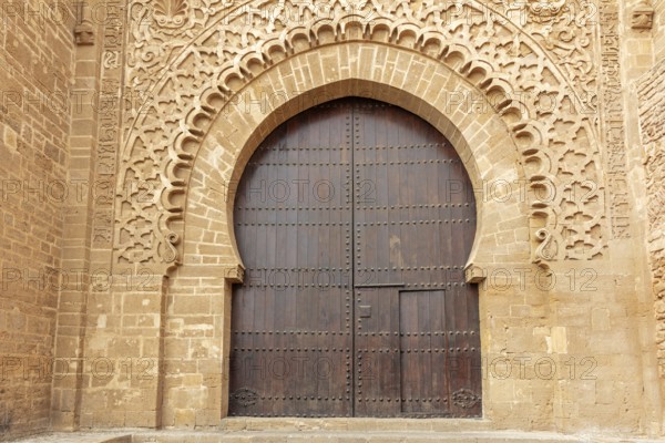 Large wooden gate with ornate stone carvings in an old wall