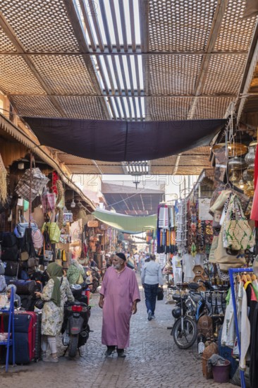 People stroll through a covered shopping alleyway with various goods