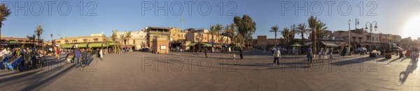 Panoramic view of a town square with shops and palm trees at sunset