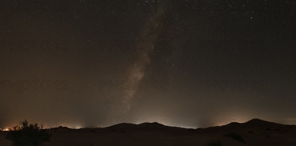 A clear night sky with the Milky Way over the tranquil desert landscape