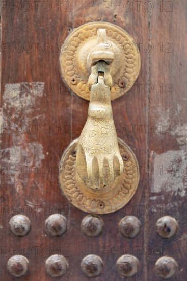 Close-up of an artistic brass door knocker in the shape of a hand