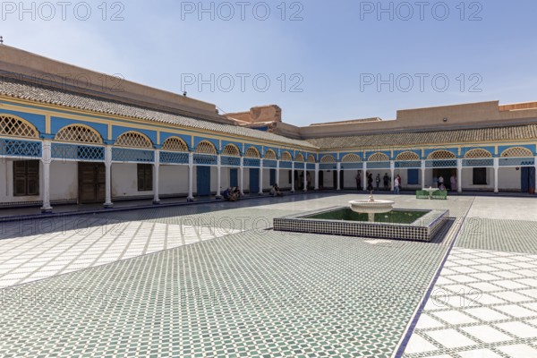 Spacious courtyard with central fountain and colorful arcades in the shadow of the sky, Bahia Palace in Marrakech, Morocco