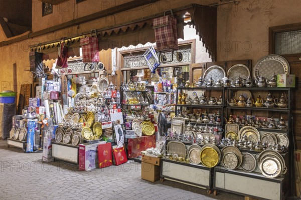 A market stall with lots of metal goods and crockery in an alley